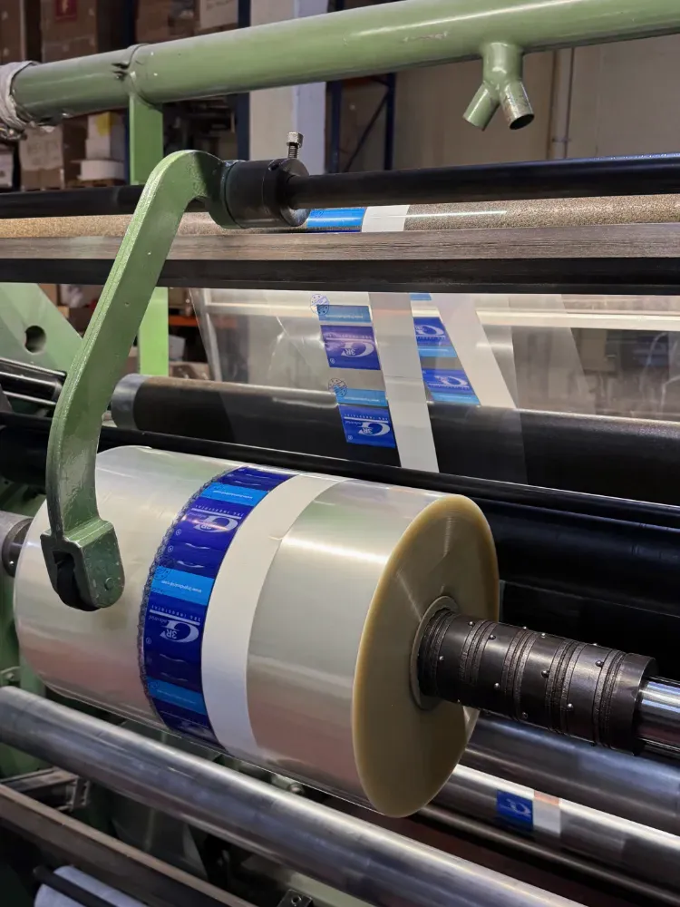 Rebobinadora cortadora industrial procesando una bobina de plástico transparente⁠